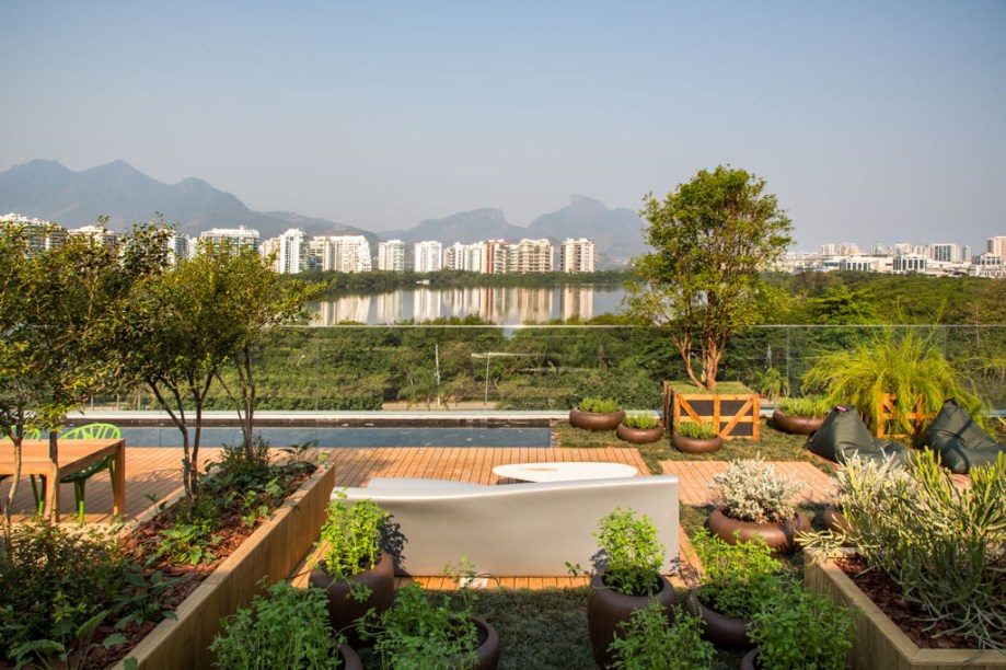 Mirante do Encontro - Os paisagistas Claudio Pedalino e Suzi Barreto pretendiam desde o início valorizar a vista. Para isso, um longo espelho d’água em frente ao deck de pedra hitam conecta o mirante à paisagem ao redor. Este espelho é a única construção em alvenaria, o restante foi todo montado para não gerar resíduos. O espaço é dividido em duas áreas de estar, uma revestida de madeira e a outra com piso intertravado em adobe assentado na areia. A dupla também utiliza diferentes tons de verde nas folhagens, o marrom acinzentado da madeira, o vermelho presente nos tijolos e o acinzentado das pedras malucas, um tipo de seixo vulcânico. A mobília combina mesa em madeira maciça natural, cadeiras em poliamida, sofá em módulos, poltrona Rio Manso (do designer Carlos Motta), mesa Braseiro em limestone cinza (Landscape), cachepots feitos de pallets e vasos cimentícios.