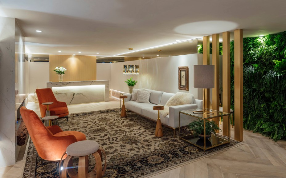 Lounge da Casa - Fernanda Paim e Elisa Martins. Quem entra no espaço já encontra a elegante bancada da bilheteria em Quartzito Bianco natural, que resume a sofisticação. No ambiente de 60 m², outra bela expressão do conceito de Casa Viva está na exuberante parede verde. As demais foram revestidas com painéis de MDF e linho, que conferem aconchego, assim como o piso em escama de peixe.