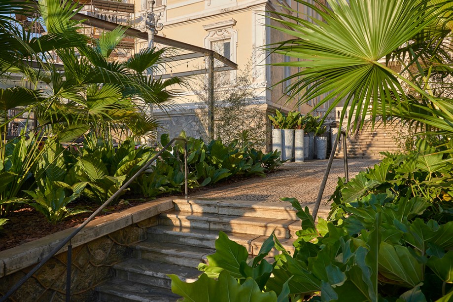 CASACOR Minas Gerais 2018. Jardim de entrada e do Pavilhão Nuvem - Felipe Fontes. Desenvolvido ora em canteiros geométricos existentes no casarão, ora em vasos de chapa metálica, o jardim potencializa a presença da vegetação e integra espaços de forma orgânica. As folhagens tropicais e a riqueza de espécies - essencialmente verdes - dão vida à composição imponente de texturas e volumetrias.