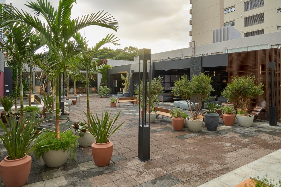 Cozy Garden – Natália Eclea e Luciana Rodrigues dos Santos. A praça de 350 m² conecta diversos ambientes, como bar, restaurante, café e loja. Também é um lugar de calmaria e aconchego, com elementos em tons quentes e o verde que acolhe. A dupla aposta em itens sustentáveis, como vasos fabricados a partir da reciclagem do plástico e móveis de cordas náuticas reutilizáveis.