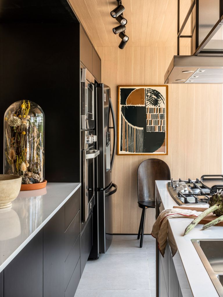 Detalhe da cozinha Tempero da vida com bancada, geladeira e parede com quadro ao fundo