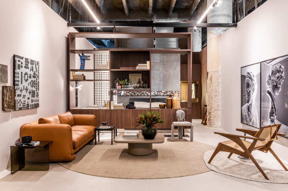 Gustavo Martins - Loft UM. Pilares e laje expostos valorizam os elementos originais do prédio e reforçam a identidade urbana do espaço de 67 m². Móveis dos designers Thiago Curioni e Roberta Baqueri atraem o olhar, assim como o piso de ladrilho hidráulico instalado junto da parede de pedra basaltina. O desejo de despertar os sentimentos de pertencimento e proteção são colocados em prática por meio da conexão entre arte e tecnologia.